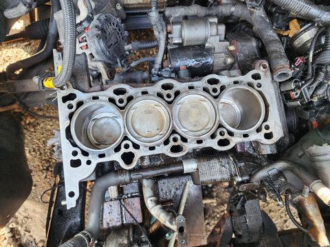 Exposed automotive engine block showing four cylinders and piston crowns.