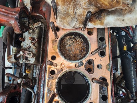 Exposed marine-engine cylinders with visible deposits on one piston crown.