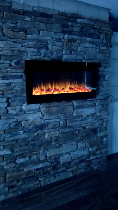 A wall-mounted fireplace with a flame display set within a textured surround.