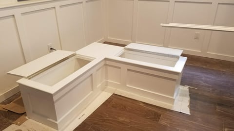 White L-shaped corner seating with raised lids revealing the storage compartments beneath.