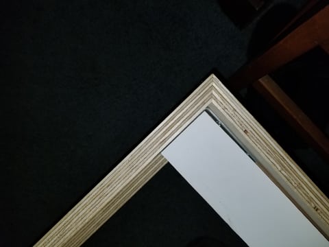 Overhead close-up of a mitered plywood corner, showing the layered edges and adjoining pieces.