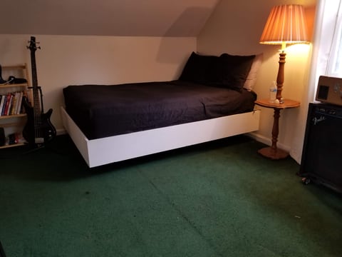 White-sided platform bed with dark bedding and a recessed base leaving a shadow beneath the frame.