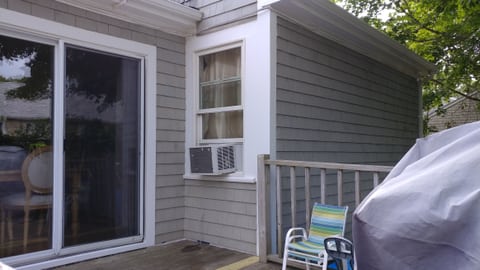 Gray shingle siding and white window trim at the exterior corner beside a sliding glass door.