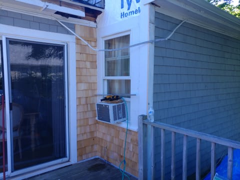 Unfinished wood shingles beside and below a white-trimmed window, with wall wrap still exposed above.
