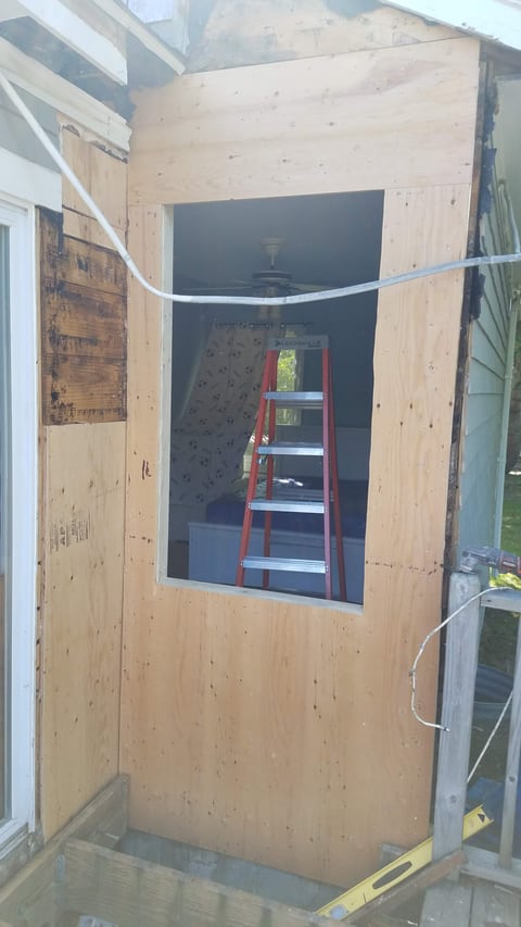 Plywood sheathing covering the exterior wall around an open window space.