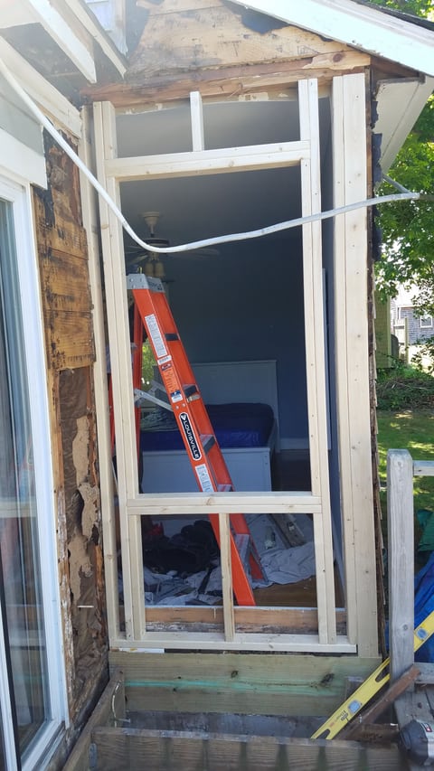 Light-colored lumber forming a window opening in an exposed exterior wall.