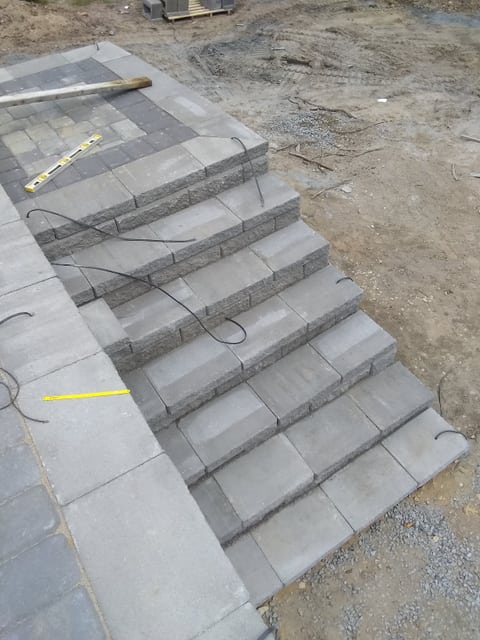 Paved steps viewed from above during construction, with a level and loose cables on the treads.